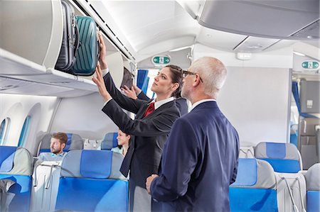 servicing a plane - Flight attendant helping businessman place luggage in overhead compartment on airplane Stock Photo - Premium Royalty-Free, Code: 6113-09059187