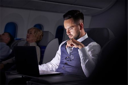 Serious businessman working at laptop on overnight airplane Photographie de stock - Premium Libres de Droits, Code: 6113-09059185