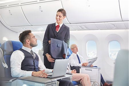 Flight attendant talking with businessman working at laptop on airplane Photographie de stock - Premium Libres de Droits, Code: 6113-09059189