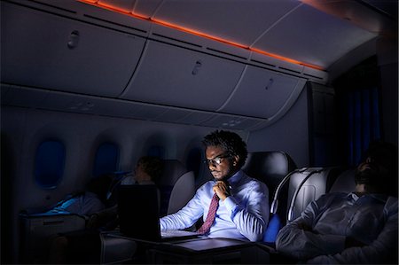 Businessman working at laptop on night airplane Stock Photo - Premium Royalty-Free, Code: 6113-09059109