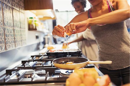 stove - Young woman cracking egg over skillet on stove in kitchen Stock Photo - Premium Royalty-Free, Code: 6113-09059257