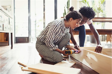 Young women assembling furniture with power drill Stock Photo - Premium Royalty-Free, Code: 6113-09059229