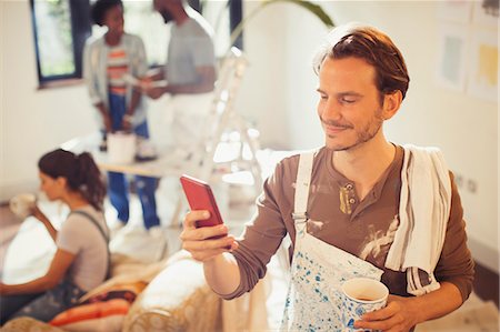 Man painting living room, drinking coffee and checking smart phone Stock Photo - Premium Royalty-Free, Code: 6113-09059342