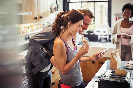 simsearch:6113-06899638,k - Smiling couple texting with smart phone, eating toast in kitchen Stock Photo - Premium Royalty-Free, Code: 6113-09059375
