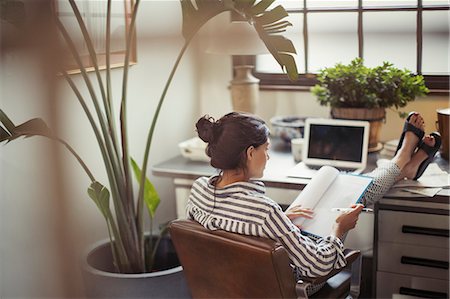 editing - Businesswoman reading paperwork with feet up on desk Stock Photo - Premium Royalty-Free, Code: 6113-09059395