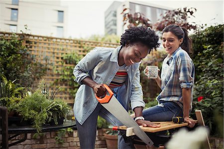simsearch:6113-07147381,k - Women drinking coffee and cutting wood with saw on patio Stock Photo - Premium Royalty-Free, Code: 6113-09059311
