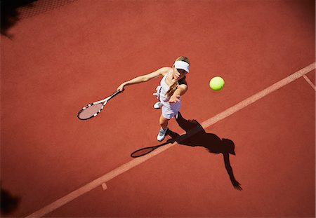 Overhead view young female tennis player playing tennis, serving the ball on sunny clay tennis court Stock Photo - Premium Royalty-Free, Code: 6113-09005069