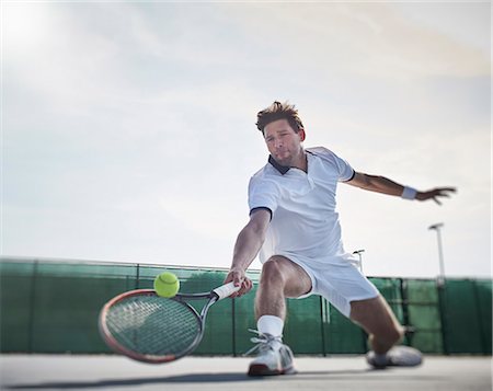 playing by the swing - Determined young male tennis player playing tennis, reaching for the ball on sunny tennis court Stock Photo - Premium Royalty-Free, Code: 6113-09005078