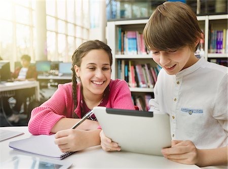 Smiling students researching, using digital tablet at table in library Photographie de stock - Premium Libres de Droits, Code: 6113-09027265