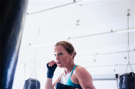 simsearch:693-08126938,k - Determined female boxer boxing at punching bag in gym Stock Photo - Premium Royalty-Free, Code: 6113-09027352