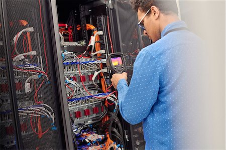 Male IT technician performing diagnostics on panel in server room Stock Photo - Premium Royalty-Free, Code: 6113-09027577