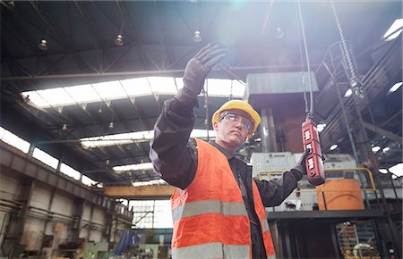 Male worker operating machinery at control panel, gesturing Stock Photo - Premium Royalty-Free, Code: 6113-09027504