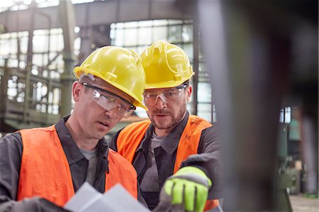 Male workers discussing paperwork in factory Stock Photo - Premium Royalty-Free, Code: 6113-09027517