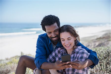 Smiling multi-ethnic couple taking selfie with cell phone on summer beach Stock Photo - Premium Royalty-Free, Code: 6113-09027642