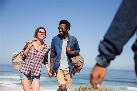 simsearch:700-03503010,k - Smiling multi-ethnic couple holding hands and walking on sunny summer ocean beach Stock Photo - Premium Royalty-Free, Code: 6113-09027645