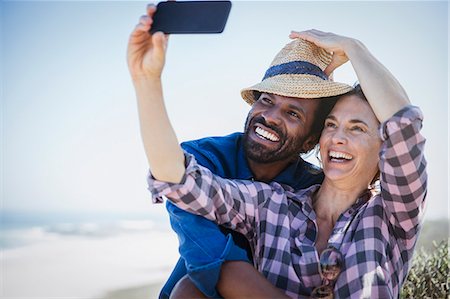 simsearch:632-05845211,k - Playful, smiling multi-ethnic couple taking selfie with camera phone on sunny summer beach Stock Photo - Premium Royalty-Free, Code: 6113-09027649