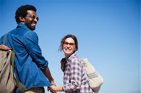 simsearch:632-05845211,k - Portrait smiling, affectionate multi-ethnic couple holding hands below sunny summer blue sky Stock Photo - Premium Royalty-Free, Code: 6113-09027664
