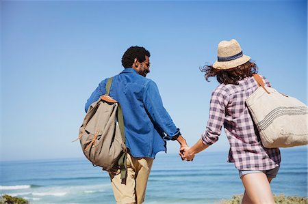 simsearch:632-05845211,k - Affectionate multi-ethnic couple holding hands, walking on sunny summer ocean beach Stock Photo - Premium Royalty-Free, Code: 6113-09027666
