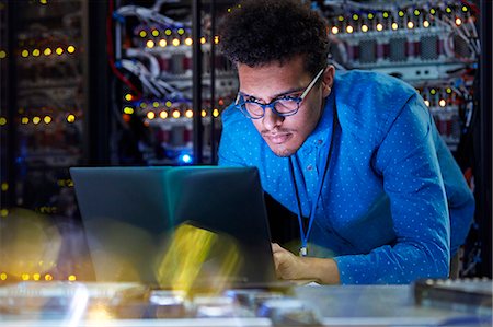 Focused male IT technician working at laptop in dark server room Photographie de stock - Premium Libres de Droits, Code: 6113-09027607