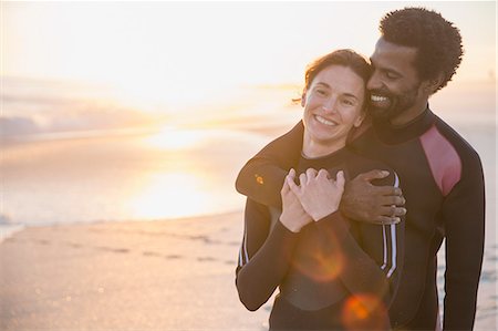simsearch:6113-07147024,k - Smiling, affectionate multi-ethnic couple in wet suits on sunny summer sunset beach Stock Photo - Premium Royalty-Free, Code: 6113-09027771