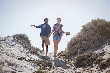 simsearch:6113-07589470,k - Playful, energetic multi-ethnic couple running and holding hands on sunny summer beach path Stock Photo - Premium Royalty-Free, Code: 6113-09027706
