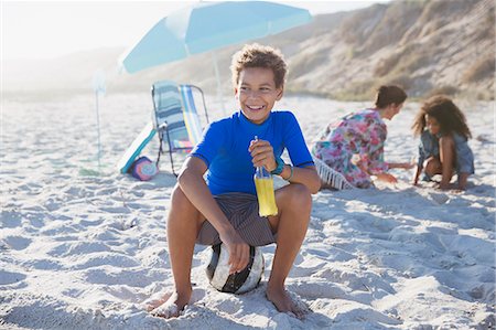 Smiling boy drinking juice on sunny summer beach Stock Photo - Premium Royalty-Free, Code: 6113-09027739