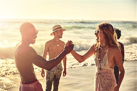 simsearch:6113-07147024,k - Playful young couple high-fiving on sunny summer ocean beach Stock Photo - Premium Royalty-Free, Code: 6113-09027847