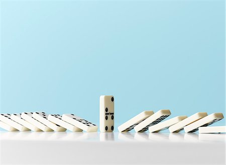 simsearch:6113-07589120,k - Dominos falling around standing domino against blue background Stock Photo - Premium Royalty-Free, Code: 6113-09027832