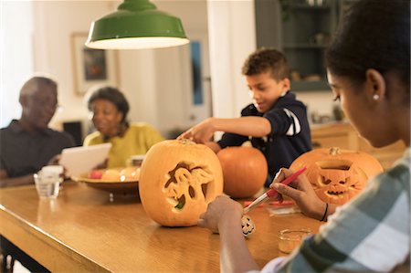 simsearch:6113-07565586,k - Grandparents at table with grandchildren carving Halloween pumpkins Stock Photo - Premium Royalty-Free, Code: 6113-09157647