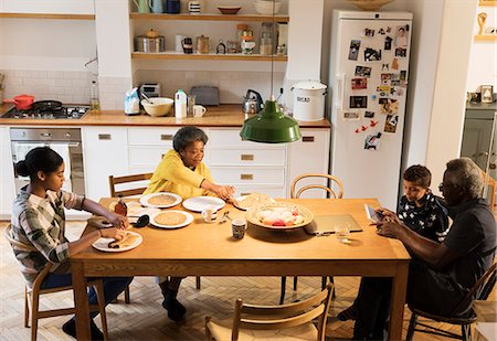 Grandparents and grandchildren eating and using digital tablet at dining table Stock Photo - Premium Royalty-Free, Code: 6113-09157659