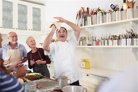 Senior friends watching playful chef tossing pizza dough in cooking class Stock Photo - Premium Royalty-Free, Code: 6113-09157734