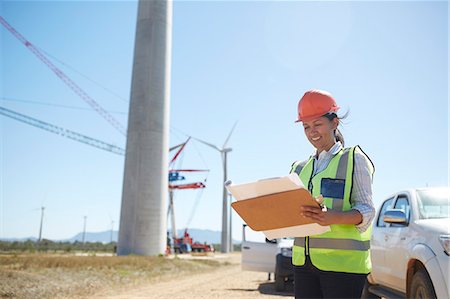 simsearch:6108-06168107,k - Smiling female engineer with blueprint at sunny wind turbine power plant Stock Photo - Premium Royalty-Free, Code: 6113-09157817