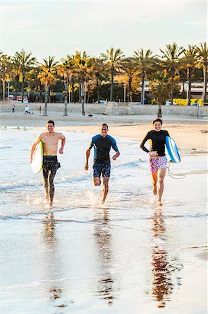 simsearch:6113-07146985,k - Enthusiastic male surfers running in surf on ocean beach Foto de stock - Sin royalties Premium, Código: 6113-09168357