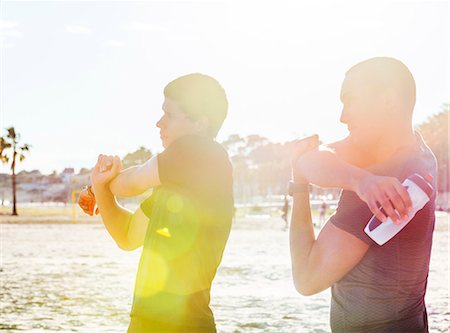 simsearch:6124-08820833,k - Male runners stretching arms on sunny beach Stock Photo - Premium Royalty-Free, Code: 6113-09168381