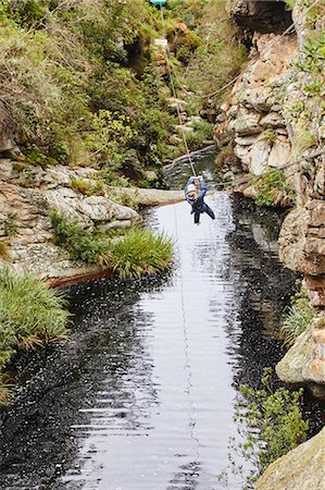 Woman zip lining over stream Stock Photo - Premium Royalty-Free, Code: 6113-09168561