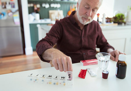 Senior man organizing pill box at kitchen table Stock Photo - Premium Royalty-Free, Code: 6113-09192057