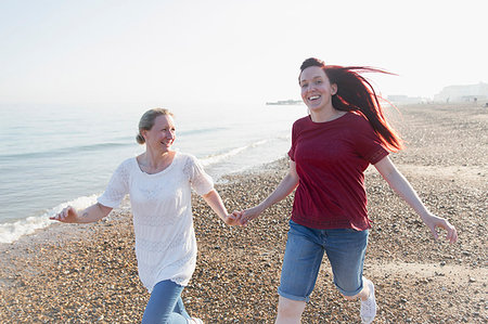 simsearch:6113-07589470,k - Playful lesbian couple running on sunny beach Stock Photo - Premium Royalty-Free, Code: 6113-09199736