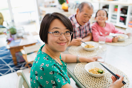 simsearch:6116-07235720,k - Portrait smiling woman eating noodles with family at table Stock Photo - Premium Royalty-Free, Code: 6113-09199884