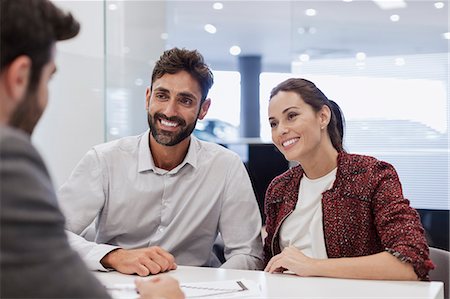 pitching - Smiling couple customers talking to car salesman in car dealership office Stock Photo - Premium Royalty-Free, Code: 6113-09111776