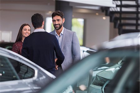 simsearch:649-07119150,k - Car salesman greeting, shaking hands with couple customers in car dealership showroom Stock Photo - Premium Royalty-Free, Code: 6113-09111842