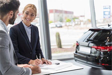simsearch:649-07119150,k - Car saleswoman and male customer signing contract paperwork in car dealership showroom Stock Photo - Premium Royalty-Free, Code: 6113-09111802