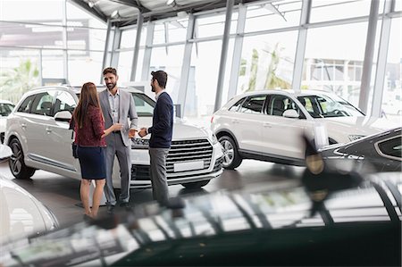 Car salesman talking to couple customers in car dealership showroom Photographie de stock - Premium Libres de Droits, Code: 6113-09111827