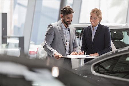 parlare - Car salesman and female customer reviewing financial contract paperwork in car dealership showroom Fotografie stock - Premium Royalty-Free, Codice: 6113-09111834