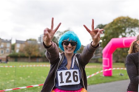 simsearch:6113-07648679,k - Portrait enthusiastic female runner in wig gesturing peace sign at charity run in park Stock Photo - Premium Royalty-Free, Code: 6113-09131359