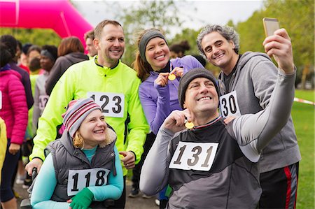 Friends with medals taking selfie at charity race in park Stock Photo - Premium Royalty-Free, Code: 6113-09131383
