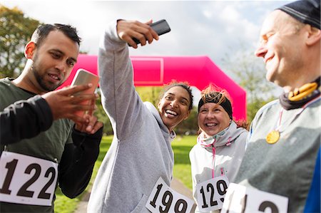 simsearch:6113-07648679,k - Happy runner friends taking selfie with camera phone at charity run in park Stock Photo - Premium Royalty-Free, Code: 6113-09131401
