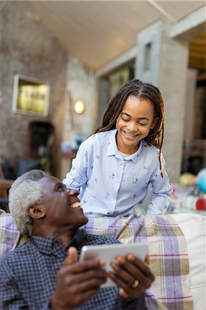 Smiling grandfather and granddaughter using digital tablet on sofa Stock Photo - Premium Royalty-Free, Code: 6113-09131593