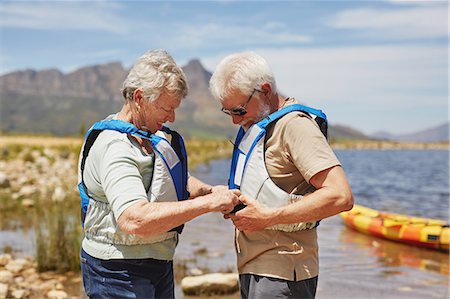 simsearch:6113-07589442,k - Active senior couple putting on life jackets, preparing for kayaking at sunny summer lakeside Stock Photo - Premium Royalty-Free, Code: 6113-09131531