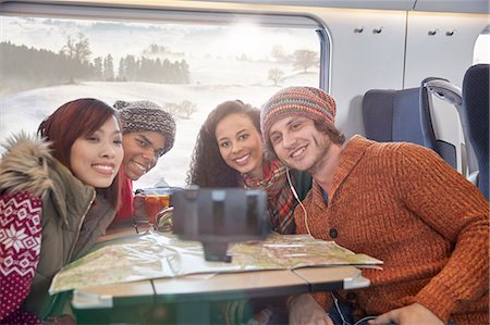 Happy young friends with map taking selfie with selfie stick on passenger train Stock Photo - Premium Royalty-Free, Code: 6113-09131607