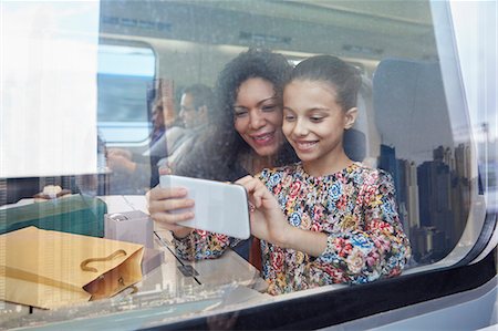 Mother and daughter using camera phone at window of passenger train Stock Photo - Premium Royalty-Free, Code: 6113-09131624